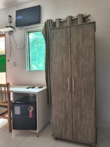 a wooden cabinet next to a desk and a window at Pousada Esperança - Areias SP in Areias