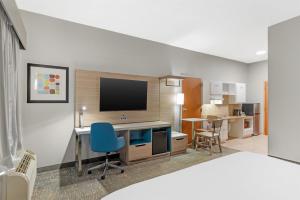 a room with a desk with a tv and a blue chair at Best Western Plus Glen Allen Inn in Richmond