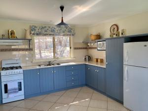 a kitchen with blue cabinets and a white refrigerator at Bay-Ann Cottage in Kingscote