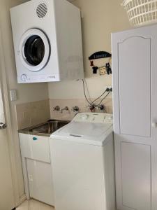 a small kitchen with a microwave and a washing machine at Bay-Ann Cottage in Kingscote
