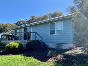 a house with a porch and stairs on it at Bay-Ann Cottage in Kingscote