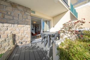 a patio with a table and a stone wall at Sea-view garden-level flat in Ploemeur