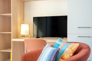 a living room with a tv and a chair at Sea-view garden-level flat in Ploemeur