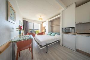 a room with a bed and a table and a kitchen at Sea-view garden-level flat in Ploemeur +16 photos