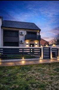 a house with a fence and lights in front of it at AR Vila Kikinda in Kikinda