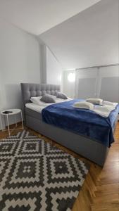a bedroom with a bed with a blue blanket and a rug at AR Vila Kikinda in Kikinda