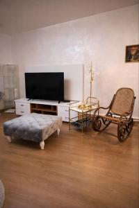 a living room with a flat screen tv and a chair at AR Vila Kikinda in Kikinda