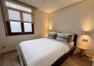 a bedroom with a white bed with pillows and a window at BILBAO ENEA - Apartamento 2 habitaciones cerca de San Mamés in Bilbao