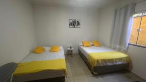 two beds in a room with yellow pillows at Casa com churrasqueira e piscina, perto de riacho in Angra dos Reis +30 photos
