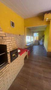 a living room with yellow walls and a brick fireplace at Casa com churrasqueira e piscina, perto de riacho in Angra dos Reis
