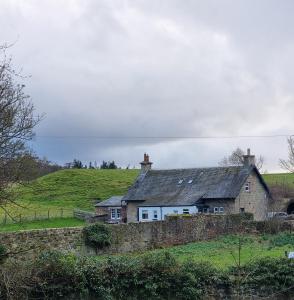 a house on top of a grassy hill at Midhope Castle Cottages in Queensferry