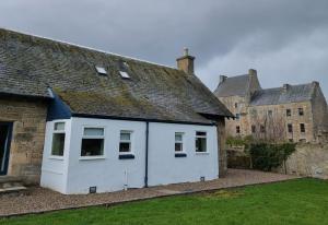 a white building with a roof in a yard at Midhope Castle Cottages in Queensferry