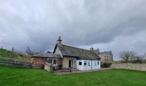 an old brick house with white doors in a field at Midhope Castle Cottages in Queensferry