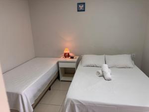 two beds in a room with a desk and a lamp at Pousada Xero in Capitólio