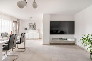 a white dining room with a large tv on a wall at Luxury Apartment Marz in Schwanau