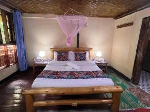 a bedroom with a bed and two tables with lamps at Ruhondeza Lodge in Buhoma