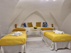 two beds in a white room with yellow sheets at Miro B&B in Lecce