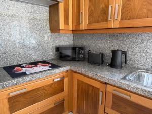 a kitchen counter with a microwave and a stove at Casa da Tininha in Alcobaça