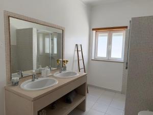 a bathroom with two sinks and a large mirror at Casa da Tininha in Alcobaça +35 photos