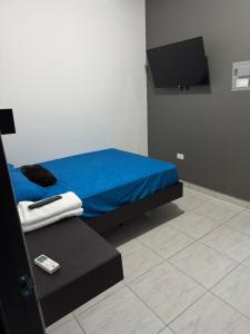 a bedroom with a blue bed and a flat screen tv at Tu refugio en el corazon de David in David