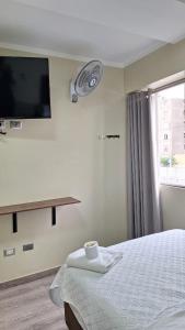 a bedroom with a bed with a tv on the wall at Hostal Plaza Grau in Lima +12 photos