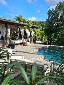 a resort with a swimming pool and a patio with chairs at Villa CYNNE Paradis Tropical in Baie-Mahault