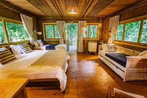 a bedroom with a large bed in a room with windows at Banana Bamboo Ecolodge in Ubatuba