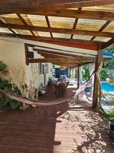 a wooden porch with a hammock and a pool at Villa CYNNE Paradis Tropical in Baie-Mahault