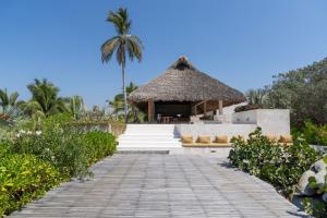 a boardwalk leading to a resort with a thatch roof at Mazul Puerto Escondido in Tlachicón