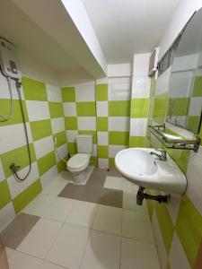 a green and white bathroom with a toilet and sink at Wheelezz in Kep