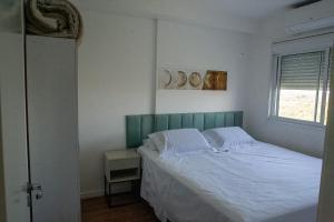 a bedroom with a bed with white sheets and a window at Areatricolor in Porto Alegre