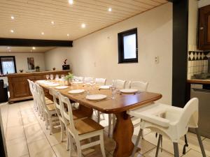 a dining room with a long table and white chairs at Annexe in Sourbrodt