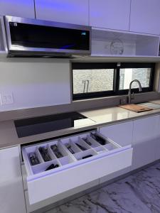 a white kitchen with a sink and a microwave at N3XT LEVEL home in Praia +15 photos