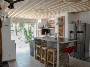 a kitchen with a counter with stools and a refrigerator at Les Dourets in Saint Antonin du Var