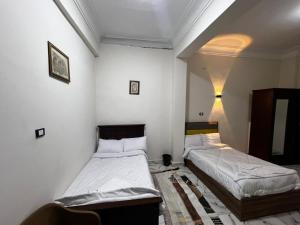 two beds in a room with white walls at tulip pyramids iin in Nazlet el-Sîsi