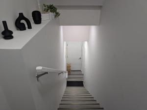 a hallway with white walls and a white stairway at Calgary Serene Suite - 19mins from airport, 1hr to Banff, 85" Cinema, Fibre WiFi, Full Kitchen in Calgary +11 photos