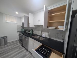 a kitchen with white cabinets and a black counter top at Calgary Serene Suite - 19mins from airport, 1hr to Banff, 85" Cinema, Fibre WiFi, Full Kitchen in Calgary