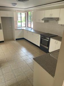 a kitchen with white cabinets and a black stove at 海边度假屋 in Sydney