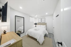 a white bedroom with a bed and a mirror at Caledon Quiet Luxury Escape 3BR Suite in Brampton