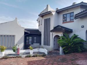a white house with a black door at Vanilla Lee Guest House in Richards Bay