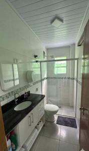 a bathroom with a shower and a sink and a toilet at Moriah Hostel e Pousada in Praia Grande +8 photos
