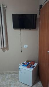a television on a wall above a refrigerator at Cananéia Apoio Tours in Cananéia