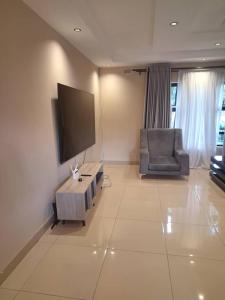 a living room with a couch and a tv and a chair at Eastview Guest House in Harare
