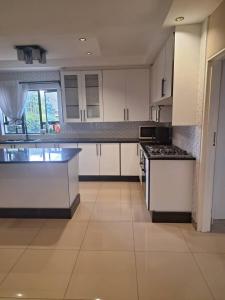 a large kitchen with white cabinets and a stove at Eastview Guest House in Harare