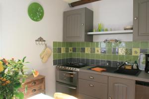 a kitchen with green tiles on the wall and a sink at Moulin De Beuzidou in Saint-Urbain