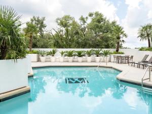 a swimming pool with blue water in a backyard with palm trees at The Whitehall Houston in Houston