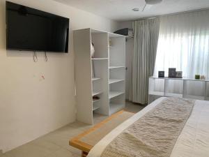 a bedroom with a bed and a television on the wall at Beautiful house with a pool in Mérida
