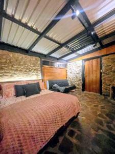 a bedroom with a large bed and a stone wall at Chalet Stonehenge in Pasto