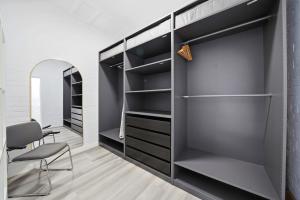 a walk in closet with black shelves and a chair at Belle Escapes - The Light House in Glenelg