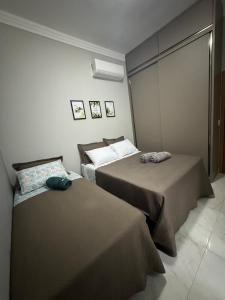 two beds in a small room withermottermottermott at Laranjeiras House in Uberaba